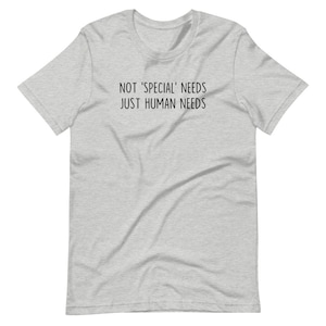 May include: A heather grey t-shirt with the text "NOT 'SPECIAL' NEEDS JUST HUMAN NEEDS" printed in black.