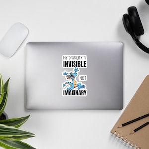May include: A sticker with a blue cartoon dragon and the text "My disability is invisible not imaginary."
