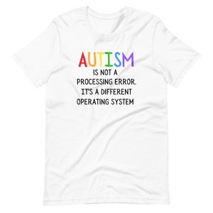 Może przedstawiać: Biały T-shirt z tekstem "AUTYZM to nie błąd przetwarzania. To inny system operacyjny" w kolorze czarnym. Słowo "AUTYZM" jest w kolorach tęczy.