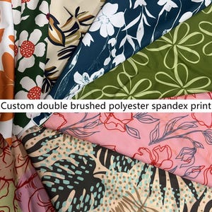 Peut inclure: Une collection d'échantillons de tissu en polyester élasthanne doublement brossé avec divers motifs, incluant des fleurs blanches sur fond vert, du bleu foncé à motifs floraux blancs, du rose à fleurs au trait rouge et des feuilles tropicales.