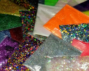 May include: A collection of small, clear plastic bags filled with various types of glitter. The glitter comes in a variety of colors, including silver, gold, green, orange, and purple. Some bags contain glitter in the shape of stars and circles.