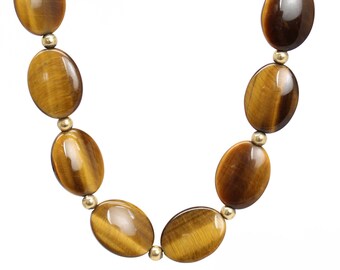 May include: A gold necklace with oval-shaped tiger's eye beads.