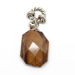 May include: A silver pendant with a brown tiger's eye gemstone and a small heart charm. The pendant is attached to a twisted silver chain.