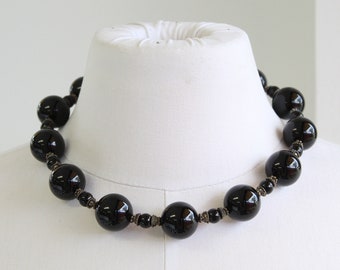 May include: A black beaded necklace with large, round beads and silver accents.
