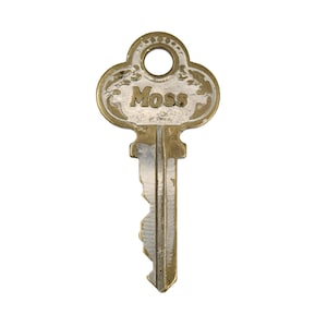 Op de afbeelding: Een vintage sleutel met de naam "Moss" gegraveerd op de kop. De sleutel heeft een decoratief, sierlijk ontwerp rond de naam en een rond gat aan de bovenkant. De sleutel is gemaakt van metaal met een goud- en zilverafwerking.
