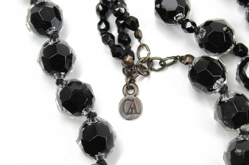 May include: A black beaded necklace with a silver charm that says "CA".