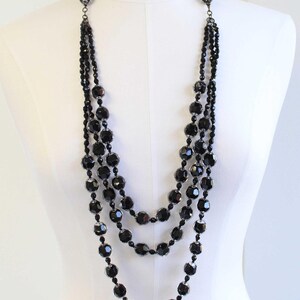 May include: A multi-strand necklace with large, faceted black beads. The necklace is made of several strands of beads, creating a layered look.