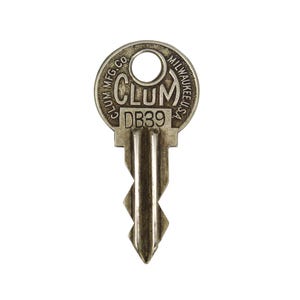 May include: A silver-coloured vintage key featuring the text "CLUM MFG. CO. MILWAUKEE U.S.A." around the circular head. The key has a rectangular base with the letters "DB39" and a ridged shaft ending in a pointed tip.
