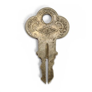 Puede incluir: Una llave de latón vintage con una cabeza en forma de trébol. La llave está grabada con el texto "Chicago Lock Company".