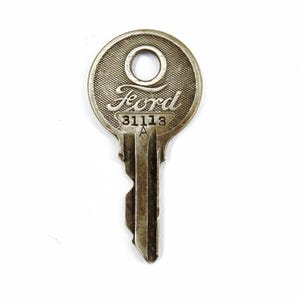 Può includere: Una chiave per auto Ford vintage argentata con la parola "Ford" e il numero "31113" incisi sulla testa.