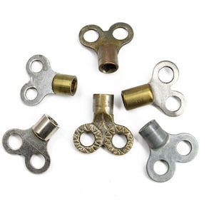 May include: Six antique brass and silver-toned keys with a double-ended T-shaped head. The keys are used for opening and closing valves.