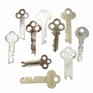 Puede incluir: Una colección de nueve llaves vintage, algunas con diseños intrincados y otras con formas simples. Las llaves son de metal y tienen un aspecto desgastado y envejecido. Algunas de las llaves tienen marcas, incluyendo "A 251" y "Mosler".