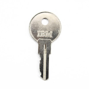 May include: A silver key with a round head and a keyway. The head of the key has the word "IBM" engraved on it.