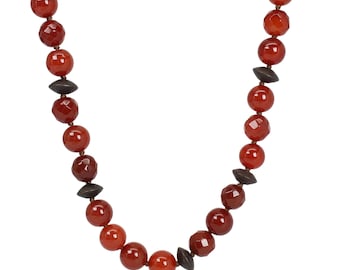May include: A necklace with reddish-orange faceted beads and dark brown, geometric-shaped beads. The necklace is strung on a brown cord. The background is white.