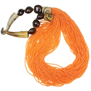 Puede incluir: Un collar de cuentas naranja con un diseño único. El collar presenta grandes cuentas de color marrón oscuro y elementos tallados con forma de hueso. El cuerpo principal del collar está compuesto por numerosos hilos de pequeñas cuentas de color naranja brillante.