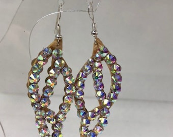 May include: A pair of dangle earrings with a gold ribbon base and iridescent rhinestones. The earrings are shaped like leaves.