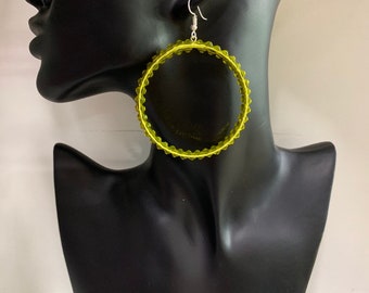 May include: Large, round, lime green hoop earrings with a silver hook.