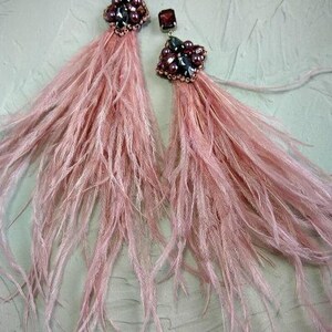 May include: A pair of pink feather earrings with dark purple and silver bead embellishments.