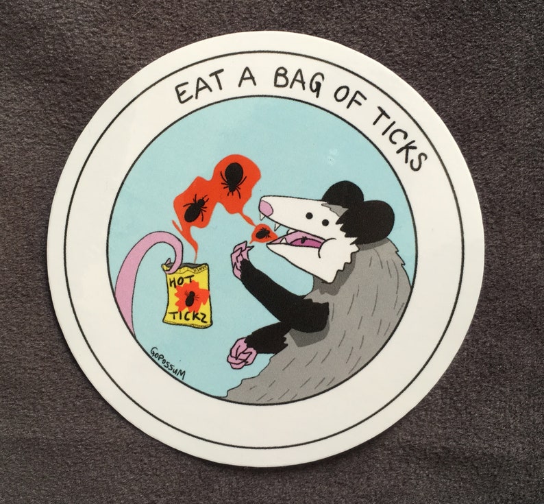May include: A white circle sticker with a black outline. Inside the circle is a cartoon illustration of a possum eating a bag of "Hot Tickz" with the text "Eat a Bag of Ticks" around the outside.