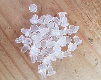 May include: A large pile of clear plastic earring backs. The backs are small and round with a small hole in the center.