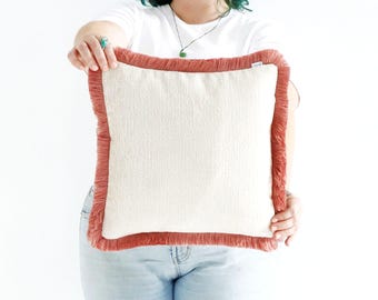 Funda de cojín hecha a mano en color rosa con flecos de algodón