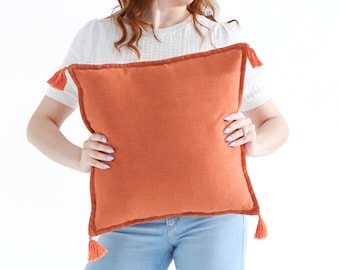 Funda de cojín texturizada de tejido liso con borlas en color naranja Yam