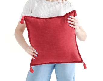 Funda de cojín de tejido liso texturizado en rojo brillante con borlas