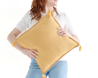 Funda de cojín texturizada de tejido liso con borlas en amarillo caléndula