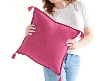 Funda de cojín texturizada de tejido liso con borlas en color rosa bombón