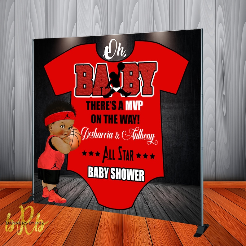 May include: A red and black baby shower backdrop with a basketball theme. The backdrop features a red onesie with the words "Oh Baby" and a basketball player silhouette. The text "There's a MVP on the way! Desharria & Anthony *** All Star *** Baby Shower" is also included.