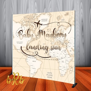 May include: A beige world map backdrop with a brown airplane icon and the text "Baby Mauboury landing soon".