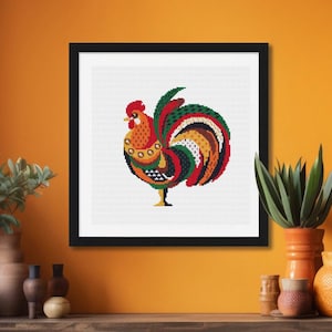 Puede incluir: Un patrón de punto de cruz de gallo colorido en un marco negro. El gallo es rojo, naranja, amarillo, verde y negro. El fondo es blanco.