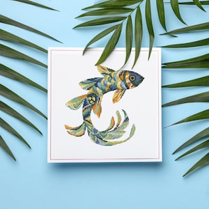 Könnte beinhalten: Ein farbenfrohes Kreuzstichmuster eines Fisches mit einem blauen, grünen, gelben und orangefarbenen Design. Der Fisch schwimmt nach rechts mit nach oben gekräuseltem Schwanz.