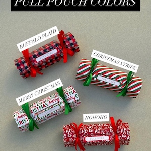 May include: Four cylindrical pull pouches with festive patterns labeled PULL POUCH COLORS. The designs include Buffalo Plaid with red ribbons, Christmas Stripe with green ribbons, Merry Christmas text with green ribbons, and Ho Ho Ho text with red ribbons.