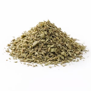 Pode incluir: Uma pilha de ervas verdes secas, provavelmente orégano ou uma erva culinária semelhante, contra um fundo branco. As ervas têm uma textura ligeiramente áspera e tons variados de verde.