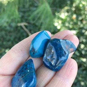 May include: Three smooth, polished blue stones with a dark blue and green color variation. The stones are tumbled and have a glossy finish.