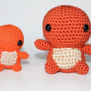 Op de afbeelding: Twee gehaakte pluche speelgoedjes in oranje en beige met zwarte ogen. Het grotere speelgoedje zit rechtop en het kleinere speelgoedje staat.