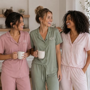 Peut inclure: Trois ensembles de pyjamas à manches courtes boutonnés avec pantalons assortis en vieux rose, vert sauge et rose clair. Les chemises présentent des cols à revers, des poches poitrine et les initiales AH et KM brodées sur les poches.