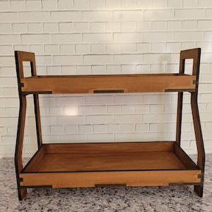 Peut inclure: Étagère en bois à deux niveaux, avec une base et un dessus rectangulaires. L'étagère présente une finition en bois naturel avec des accents marron foncé. La conception comprend un cadre ouvert simple avec deux plateaux rectangulaires.