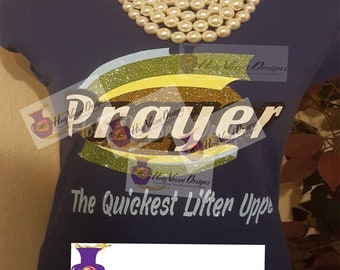 Könnte beinhalten: Marineblaues T-Shirt mit dem Wort "Prayer" in einem glitzernden Design. Der Text "The Quickest Lifter Upper" steht darunter. Eine Perlenkette ist ebenfalls zu sehen.
