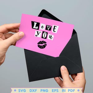 Pode incluir: Cart&atilde;o rosa com as palavras "Love You" em letras pretas recortadas e uma impress&atilde;o de l&aacute;bios pretos. O cart&atilde;o est&aacute; em um envelope preto.