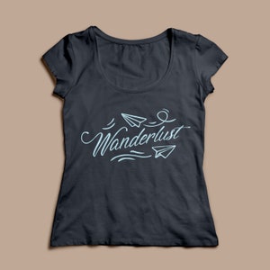 May include: Dark gray scoop neck t-shirt with the word "Wanderlust" in light blue script, accompanied by paper airplane illustrations. The shirt is a solid color and has short sleeves.