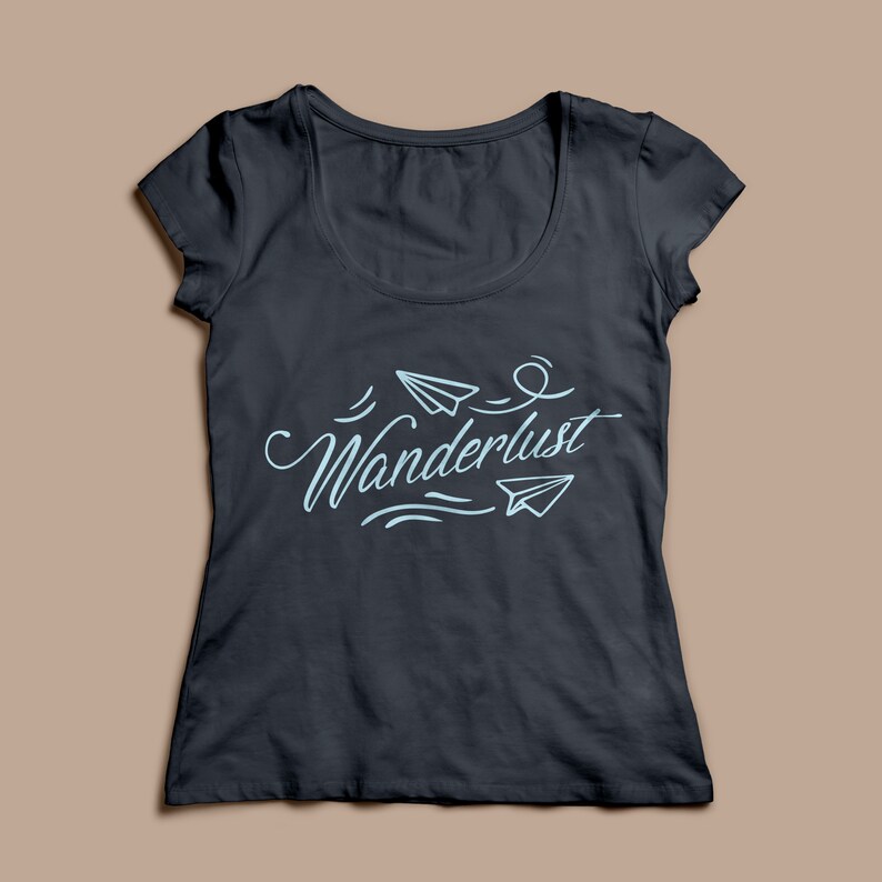 May include: Dark gray scoop neck t-shirt with the word "Wanderlust" in light blue script, accompanied by paper airplane illustrations. The shirt is a solid color and has short sleeves.