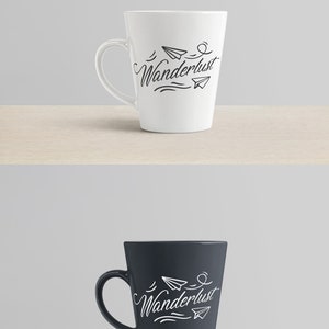 May include: Two ceramic mugs, one white and one dark blue, each with a curved handle. The mugs feature the word "Wanderlust" in cursive, along with paper airplane illustrations. The mugs are on a light wooden surface.