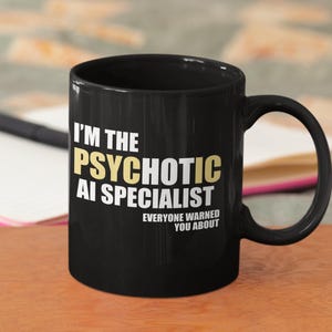 May include: Black coffee mug with white text that reads "I'm the Psychotic AI Specialist. Everyone warned you about."