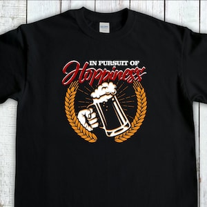 May include: Black t-shirt featuring a graphic of a beer mug with the text "In Pursuit of Happiness" above it.