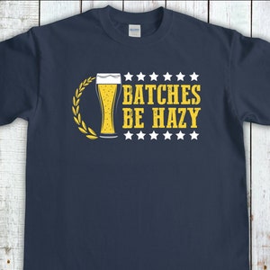 May include: Navy blue t-shirt featuring a yellow graphic of a beer glass and the text "Batches Be Hazy" surrounded by white stars.