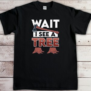 May include: Black t-shirt with a white graphic of an axe and tree stumps. The text "WAIT I SEE A TREE" is printed in white on the shirt.