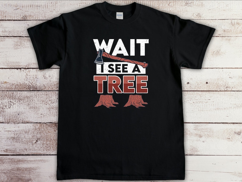 May include: Black t-shirt with a white graphic of an axe and tree stumps. The text "WAIT I SEE A TREE" is printed in white on the shirt.