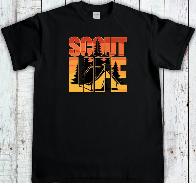 May include: Black t-shirt with the words "SCOUT LIFE" in orange and red block letters. The word "LIFE" features a camping scene with trees and a tent in a yellow and orange gradient.